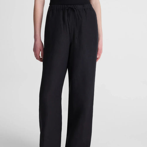 A model wearing black wide-leg drawstring pants and black sandals, shown from the waist down against a light gray studio background.