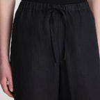 Close-up of a person wearing black wide-leg drawstring pants, showing the elastic waistband and fabric texture.