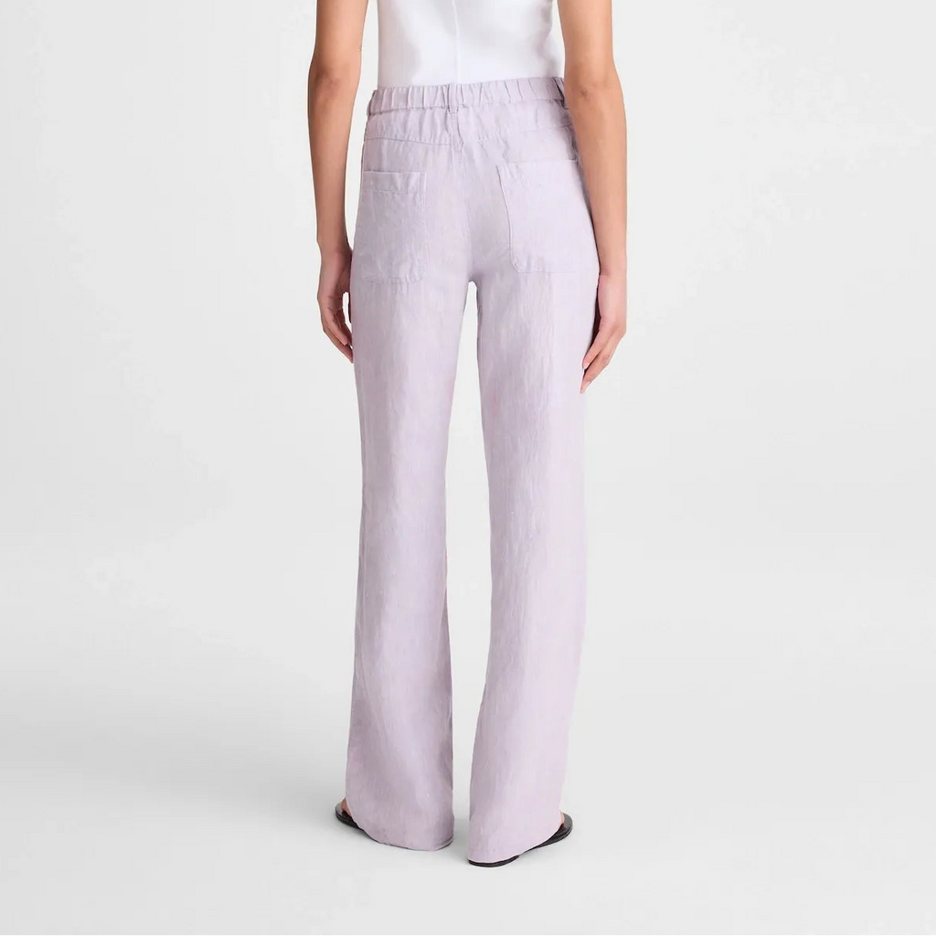 A model shown from the back wearing a sleeveless white top and light lavender wide-leg trousers against a plain light gray studio background.
