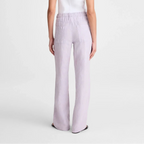 A model shown from the back wearing a sleeveless white top and light lavender wide-leg trousers against a plain light gray studio background.