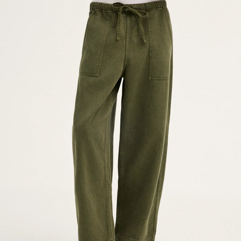 Olive green wide-leg pants with an elastic drawstring waist and side pockets, shown on a model wearing black flip-flop sandals against a plain white studio background.