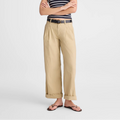 A woman modeling a navy and white striped strapless top, beige wide-leg cropped pants, a thin black belt, and dark brown sandals against a light gray studio background.